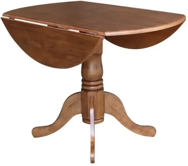John Thomas Dining Essentials Round Drop Leaf Pedestal Table in Bourbon Oak